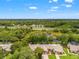 An aerial view of townhomes nestled among mature trees and a small pond, with a highway in the background at 7512 Heather Walk Dr, Weeki Wachee, FL 34613