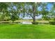 Expansive backyard featuring lush green grass, mature trees, and serene pond views at 7512 Heather Walk Dr, Weeki Wachee, FL 34613