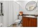 Bright bathroom featuring a round mirror, modern vanity, and a shower with white waffle curtain at 7512 Heather Walk Dr, Weeki Wachee, FL 34613