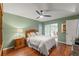 Cozy bedroom with hardwood floors, a ceiling fan, and sliding door access to a bright sunroom or outdoor area at 7512 Heather Walk Dr, Weeki Wachee, FL 34613
