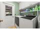 Practical laundry room with modern appliances, overhead storage, and convenient access to the garage at 7512 Heather Walk Dr, Weeki Wachee, FL 34613