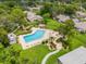 Aerial view of a community pool with lounge chairs, a hot tub, and lush landscaping at 7512 Heather Walk Dr, Weeki Wachee, FL 34613