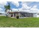Beautiful backyard features a screened-in pool, lush green lawn, palm trees, and outdoor dining area at 7520 Mako Dr, Hudson, FL 34667