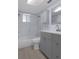 Updated bathroom featuring a shower-tub combo with a glass door, gray vanity, and bright natural light at 7520 Mako Dr, Hudson, FL 34667