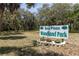 Sea Pines Woodland Park sign surrounded by vibrant flowers and lush greenery provides a welcoming entrance at 7520 Mako Dr, Hudson, FL 34667