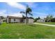 Classic single-story home featuring a well-manicured lawn, complemented by a mature palm tree at 7520 Mako Dr, Hudson, FL 34667