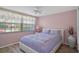 Bedroom with large window, light pink walls and decorative bedding at 8021 Wildflower Row, Hudson, FL 34667