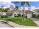 Charming single-story home featuring a well-maintained lawn, blue trim, and a pergola-covered entrance at 8021 Wildflower Row, Hudson, FL 34667