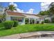 Charming single-story home featuring a well-maintained lawn, blue trim, and a pergola-covered entrance at 8021 Wildflower Row, Hudson, FL 34667