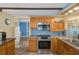 Cozy kitchen features stainless steel appliances, wooden cabinetry, and blue tile backsplash at 8021 Wildflower Row, Hudson, FL 34667