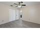 Spacious bedroom with gray wood-look floors, fan, closet, and ensuite bath at 8431 Spring Hill Dr, Spring Hill, FL 34608