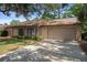 Inviting front exterior featuring a two-car garage, brick facade, and well-manicured landscaping at 8431 Spring Hill Dr, Spring Hill, FL 34608