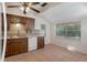 Eat-in kitchen features wood cabinets, tile backsplash, white appliances, and a window with backyard views at 8431 Spring Hill Dr, Spring Hill, FL 34608