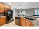 Well-lit kitchen with granite countertops, tile floors, black appliances, and wood cabinets at 9527 Southern Charm Cir, Brooksville, FL 34613