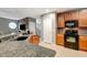 Open-concept kitchen showcases wood cabinets, granite countertops, and black appliances at 9527 Southern Charm Cir, Brooksville, FL 34613