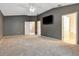 Large main bedroom with neutral carpet, ceiling fan, TV, and adjoining bathroom at 9527 Southern Charm Cir, Brooksville, FL 34613
