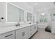 Bright bathroom with double vanity, large mirrors, chandelier, and a standalone tub by the window at 9810 Compass Point Way, Tampa, FL 33615