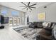 Spacious living room with light wood floors, modern ceiling fan, large windows, and comfortable dark sectional sofa at 9810 Compass Point Way, Tampa, FL 33615