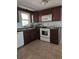 Traditional kitchen features brown cabinets, white appliances, tile floor, and natural light at 6339 Delaware Ave, New Port Richey, FL 34653