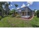 Landscaped backyard with a screened pool, lawn, and tropical plants offers outdoor enjoyment at 10344 Tecoma Dr, Trinity, FL 34655