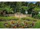 Fox Wood community entrance with colorful flowers, lush shrubbery, and mature trees at 10344 Tecoma Dr, Trinity, FL 34655