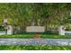An elegant community entrance featuring stone pillars, an iron gate, and lush landscaping under mature trees at 10344 Tecoma Dr, Trinity, FL 34655