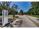 Gated community visitors entrance with a stop sign and camera for enhanced security, and tree-lined street at 10344 Tecoma Dr, Trinity, FL 34655