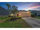 Charming single-Gathering home features a well-manicured lawn and a two-car garage against a colorful sunset sky at 10344 Tecoma Dr, Trinity, FL 34655