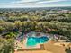 Aerial view of pool with lounge chairs, umbrellas, garden and trees in a community at 11350 Copley Ct, Spring Hill, FL 34609
