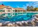 Beautiful community pool surrounded by ample seating, a clubhouse, and lush landscaping at 11350 Copley Ct, Spring Hill, FL 34609