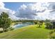 Picturesque backyard view featuring a well-maintained lawn, lush landscaping, and a serene lake at 11611 Callisia Dr, Odessa, FL 33556
