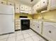 Efficient kitchen with white cabinets and appliances including a white refrigerator and black stove at 11911 Bayonet Ln, New Port Richey, FL 34654