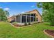 Back exterior of home featuring a screened lanai, well maintained lawn and shrubbery, and a brick border at 12071 Wexford Blvd, Spring Hill, FL 34609