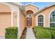 Inviting home entrance with arched doorway, decorative windows, and manicured bushes at 12071 Wexford Blvd, Spring Hill, FL 34609