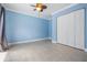 Bright bedroom features blue walls, neutral tile floors, a ceiling fan, and a closet with bi-fold doors at 1222 Starboard Ky, Tarpon Springs, FL 34689