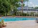 Community pool surrounded by lush landscaping and a black iron fence at 12408 Country White Cir, Tampa, FL 33635