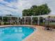 Community pool with tables, chairs and lounge chairs by a pergola at 12408 Country White Cir, Tampa, FL 33635