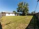 Wide backyard with a large tree, wood fence, and the home's exterior for outdoor enjoyment and privacy at 1249 Honor Dr, Holiday, FL 34690