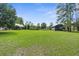 Lush backyard with large lawn area, bordered by mature trees and a storage shed with ample space at 1253 Culbreath Rd, Brooksville, FL 34602
