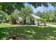 Well-manicured lawn with beautiful landscaping and a white home with a metal roof and a circular driveway at 1253 Culbreath Rd, Brooksville, FL 34602