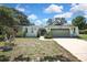 An exterior view of the home featuring a two-car garage, arched entry, and lush greenery at 12722 Oak Tree Dr, Hudson, FL 34667