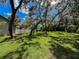 A spacious backyard featuring lush green grass, shade trees, and a white picket fence at 13627 Glaze Brook Dr, Hudson, FL 34667