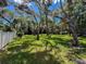 Large backyard featuring mature trees, green grass, and a white picket fence for privacy at 13627 Glaze Brook Dr, Hudson, FL 34667