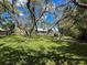 An expansive green lawn is surrounded by mature trees, providing a private backyard setting at 13627 Glaze Brook Dr, Hudson, FL 34667
