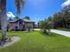 Exterior featuring a lush green front lawn and mature palm trees against a blue sky at 13627 Glaze Brook Dr, Hudson, FL 34667
