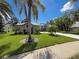 Well-maintained exterior with a lush front lawn, complemented by mature palm trees at 13627 Glaze Brook Dr, Hudson, FL 34667
