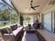 Comfortable sunroom featuring wicker sofa, ottoman, ceiling fan, and access to the outdoors at 13627 Glaze Brook Dr, Hudson, FL 34667