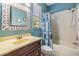 A bathroom with a decorative mirror, framed prints, and a blue shower curtain at 1418 Halapa Way, Trinity, FL 34655