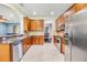 Modern kitchen with stainless steel appliances, wooden cabinets, granite countertops, and tile flooring at 1418 Halapa Way, Trinity, FL 34655