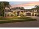 Elegant single-story home with mature palms, a three-car garage, and manicured landscaping at sunset at 15413 Azra Dr, Odessa, FL 33556